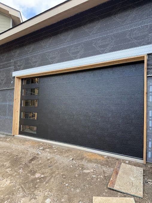 Modern black garage door with full-view windows on a contemporary home