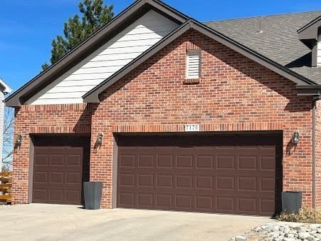 Carriage-style brown paneled doors on a Denver brick home