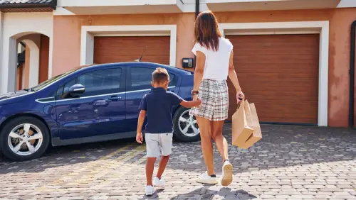 Family standing with a garage door technician in front of their home with brown garage doors, representing family-owned service