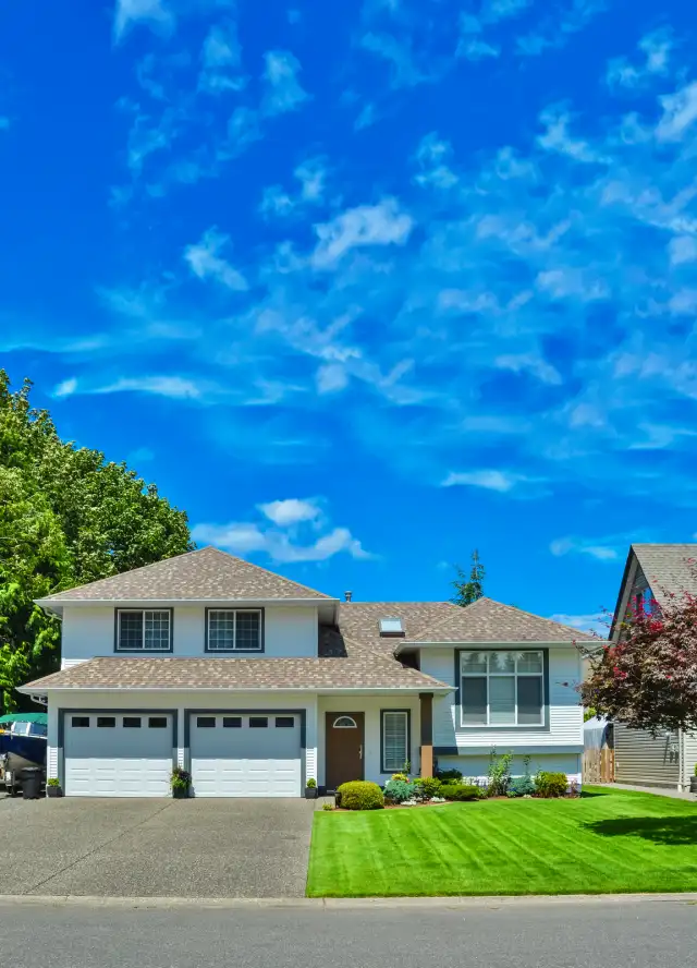 Residential home with attached two-car garage featuring white doors and well-maintained landscaping